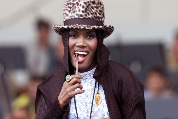 Grace Jones mit Leopardenhut und einem Gegenstand im Mund.