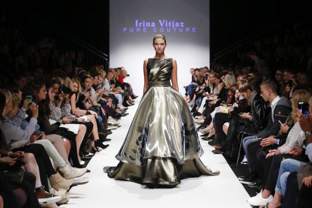 Ein Model präsentiert ein Kleid von Irina Vitjaz auf dem Laufsteg vor Publikum.