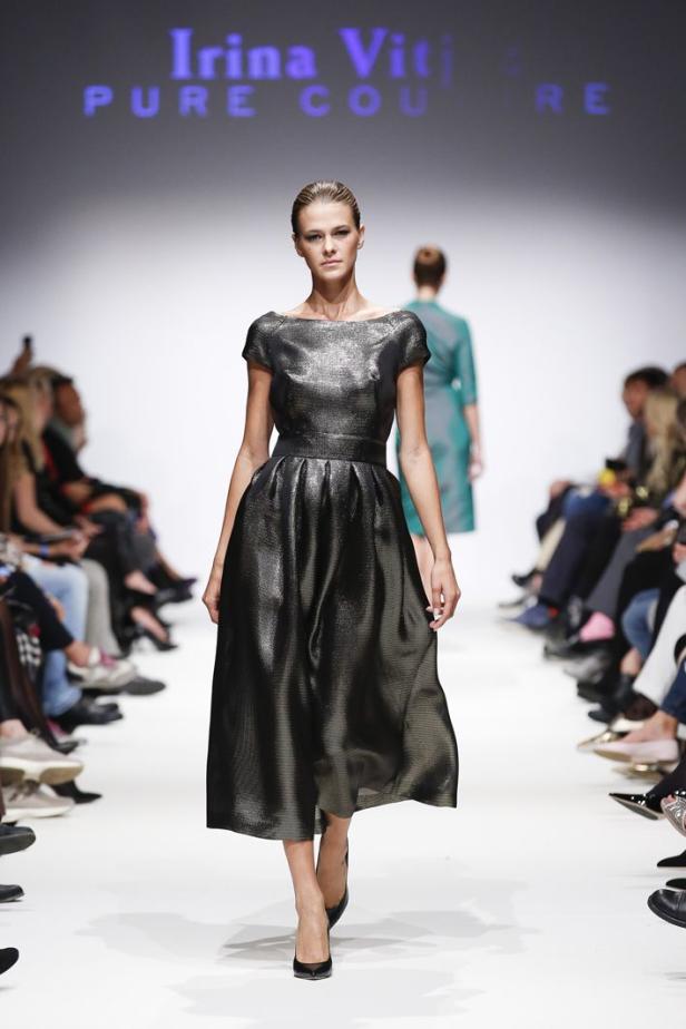 Ein Model präsentiert ein glänzendes, knielanges Kleid auf dem Laufsteg von Irina Viti Pure Couture.
