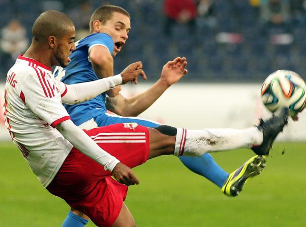 Ein Fußballspieler schießt den Ball, während ein anderer Spieler zusieht.
