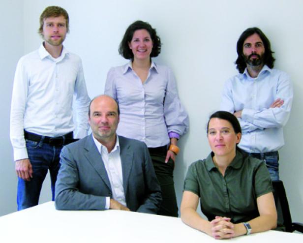 Fünf Personen posieren für ein Gruppenfoto an einem Tisch.