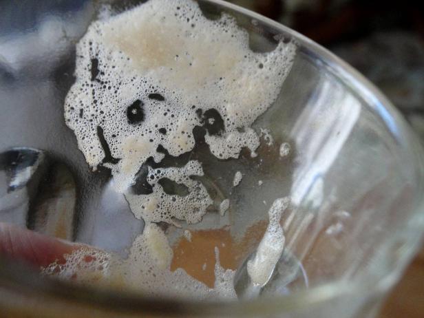 Ein leeres Glas mit Resten von Schaum darin.