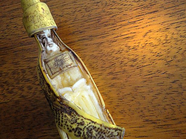 Eine geöffnete Bananenschale liegt auf einem Holztisch.