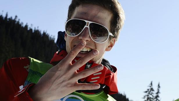 Ein Mann mit Sonnenbrille zeigt vier Finger in einer winterlichen Umgebung.