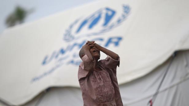 Ein weinendes Kind steht vor einem Zelt des UNHCR.