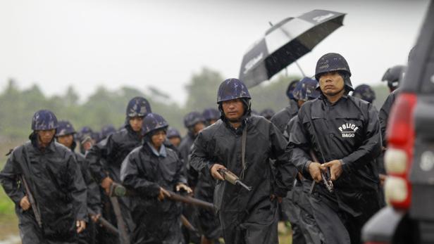 Eine Gruppe von Polizisten in Bago, Myanmar, marschiert im Regen.