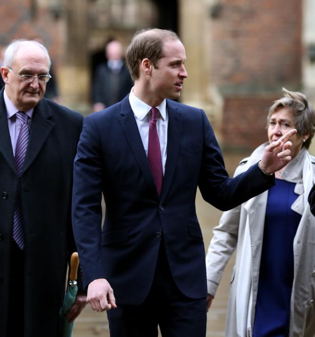 Prinz William gestikuliert, während er von zwei Personen begleitet wird.