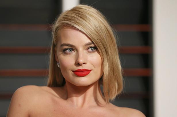 Porträt von Margot Robbie mit blonden Haaren und rotem Lippenstift.