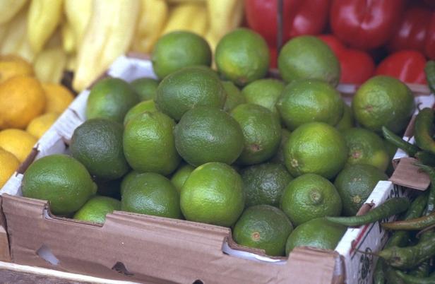 Eine Kiste voller Limetten auf einem Marktstand.