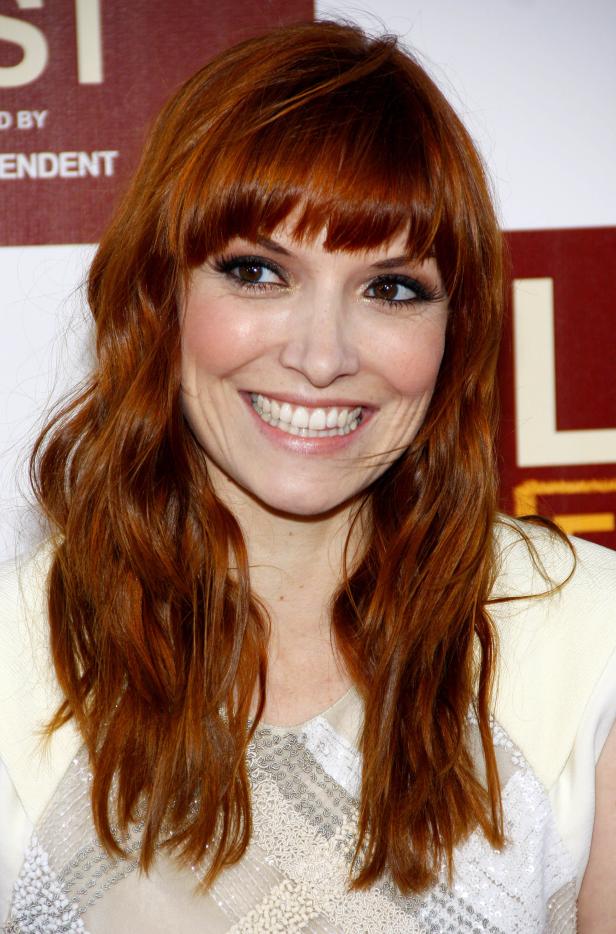 Nahaufnahme von Sara Rue mit roten Haaren und einem hellen Kleid.