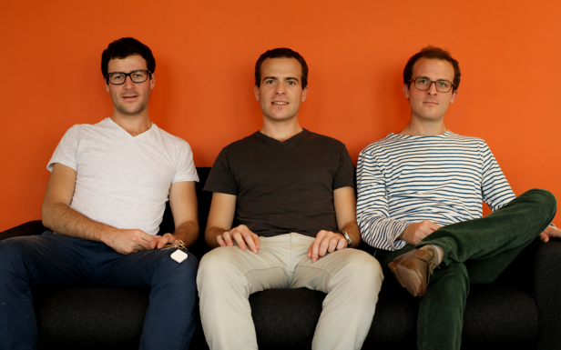 Lussato Bruni, Hugo und Thèo - Gründer Wistiki - Bild 2 Drei Männer sitzen auf einer schwarzen Couch vor einer orangefarbenen Wand.