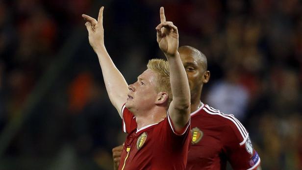 Kevin De Bruyne jubelt mit erhobenen Händen in einem roten Fußballtrikot.