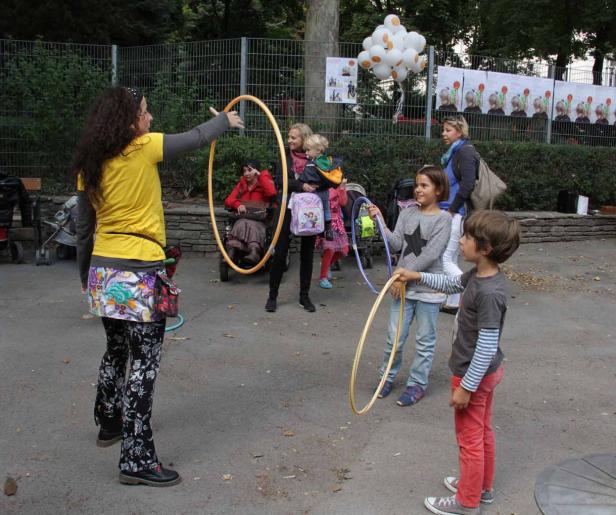 Eine Frau leitet Kinder beim Spielen mit Hula-Hoop-Reifen im Freien an.