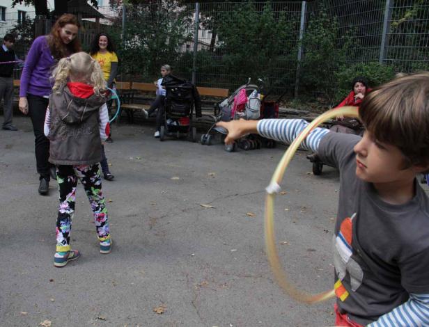 Ein Junge wirft einen Hula-Hoop-Reifen, während andere Kinder und Erwachsene im Hintergrund stehen.