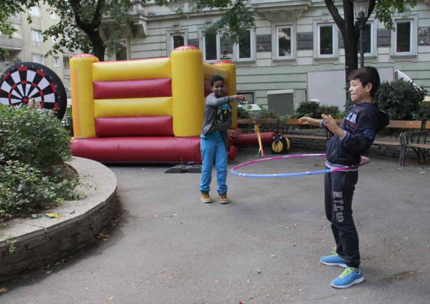 Zwei Jungen spielen mit einem Hula-Hoop-Reifen und einem aufblasbaren Dartspiel im Park.
