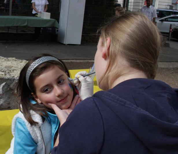 Ein Mädchen wird von einer Frau mit Farbe im Gesicht bemalt.