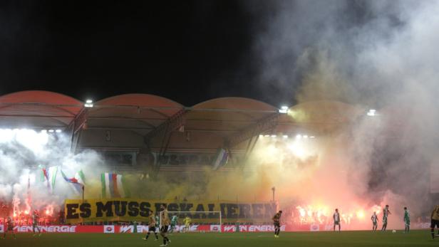 Während eines Fußballspiels zünden Fans Rauchbomben und Bengalos.