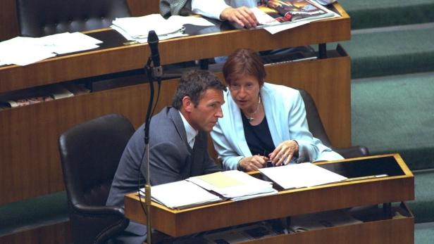 Ein Mann und eine Frau sitzen an einem Tisch und diskutieren über Dokumente.