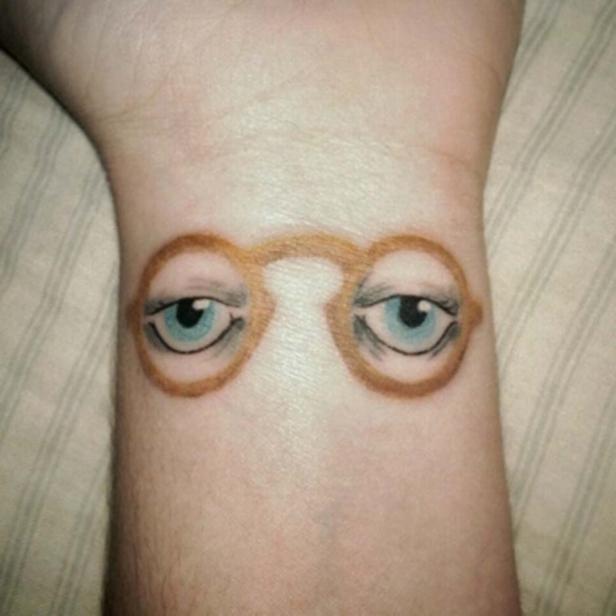 Ein Tattoo auf einem Handgelenk zeigt eine Brille mit Augen darin.
