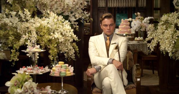 Leonardo DiCaprio als Jay Gatsby, umgeben von Blumen und Süßigkeiten.