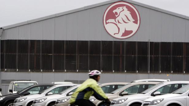 Eine Person fährt mit dem Fahrrad vor einem Gebäude mit dem Holden-Logo.