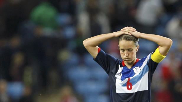 Eine Fußballspielerin von Großbritannien mit hängendem Kopf und gelber Armbinde.