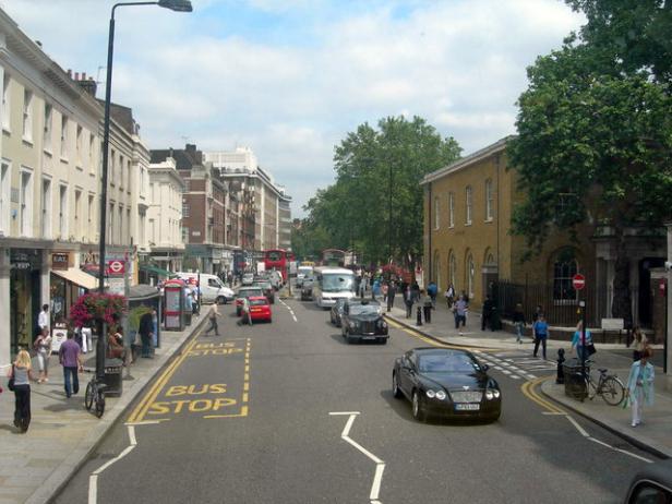 Eine belebte Straße in London mit Bussen, Autos und Fußgängern.