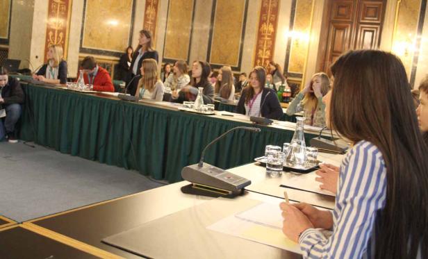 Teilnehmer sitzen an Tischen während einer Konferenz in einem eleganten Saal.
