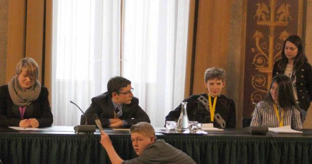 Eine Gruppe junger Leute sitzt an einem Tisch während einer Veranstaltung.