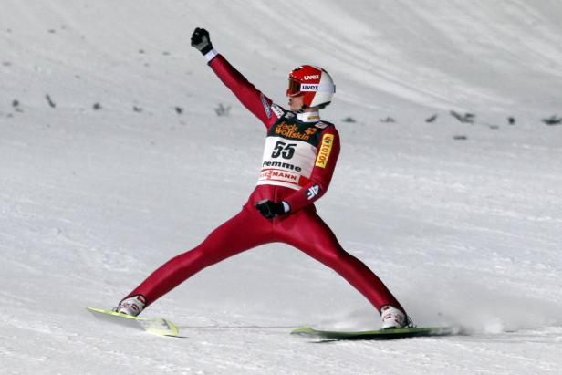 Ein Skispringer jubelt nach einem Sprung im Schnee.