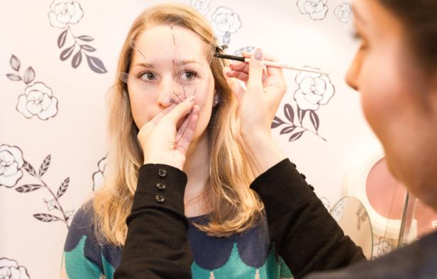 Eine Frau erhält eine Augenbrauenbehandlung mit einer Schablone.