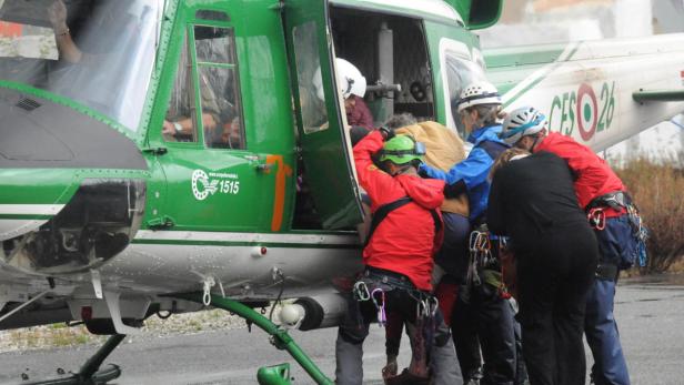 Bergretter steigen in einen grünen Hubschrauber des Corpo Forestale ein.