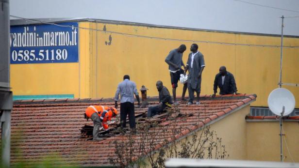 Mehrere Männer reparieren ein Ziegeldach.