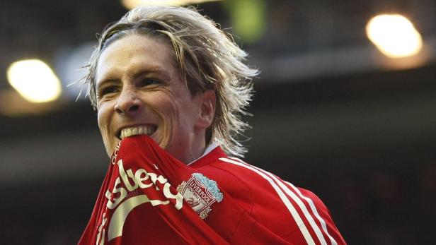 Fernando Torres hält sein Liverpool-Trikot mit den Zähnen fest und lächelt.