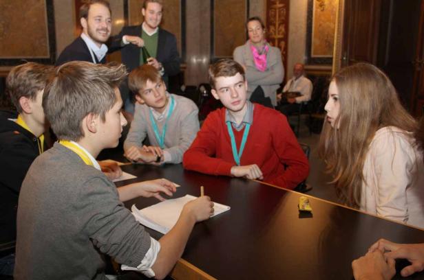 Eine Gruppe junger Leute sitzt an einem Tisch und diskutiert.