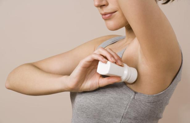Eine Frau benutzt ein Roll-On-Deodorant unter ihrer Achsel.