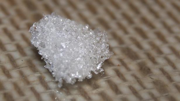 Ein Haufen glitzernder Eis- oder Schneekristalle liegt auf einer Oberfläche.