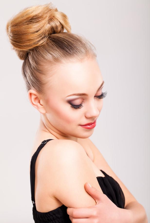 Eine Frau mit blondem Haar und auffälligem Make-up blickt nach unten.