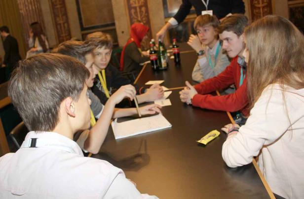 Eine Gruppe Jugendlicher sitzt an einem Tisch und diskutiert.