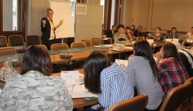 Eine Frau hält eine Präsentation vor einer Gruppe von Zuhörern in einem Konferenzraum.