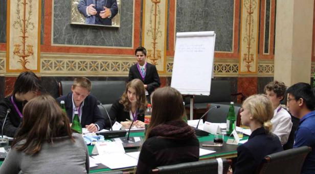 Eine Gruppe junger Leute sitzt an einem Tisch während einer Konferenz.