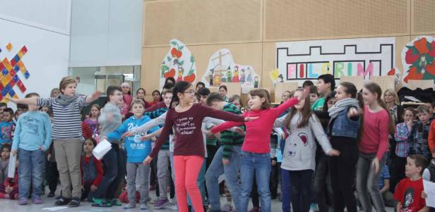 Eine Gruppe von Schulkindern führt ein Theaterstück auf einer Bühne auf.