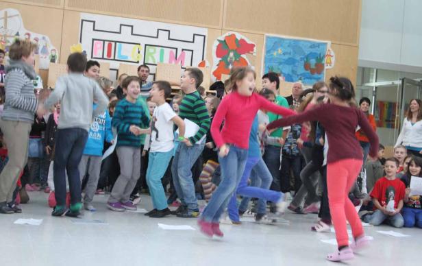 Eine Gruppe aufgeregter Kinder tanzt und springt in einem Raum.