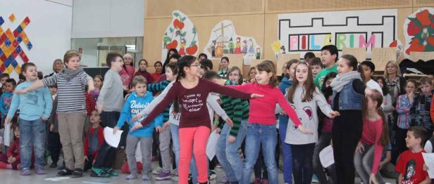 Eine Gruppe von Kindern führt ein Theaterstück oder eine Tanzperformance auf einer Bühne auf.