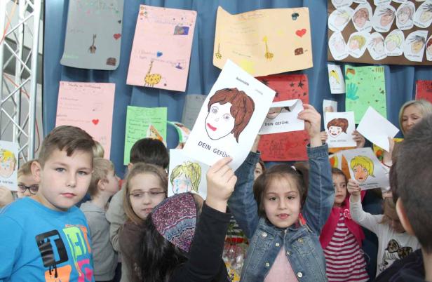 Eine Gruppe von Kindern präsentiert ihre selbstgemalten Porträts zum Thema „Dein Gefühl“.