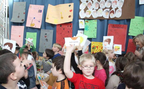 Eine Gruppe von Kindern präsentiert ihre selbstgemalten Bilder zum Thema „Dein Gefühl“.