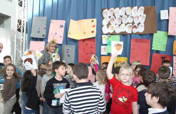 Eine Gruppe von Kindern steht vor einer Wand mit bunten Zeichnungen.