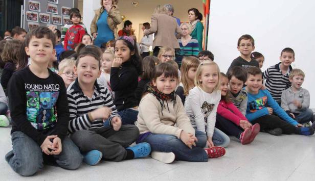 Eine Gruppe von Grundschulkindern sitzt auf dem Boden.
