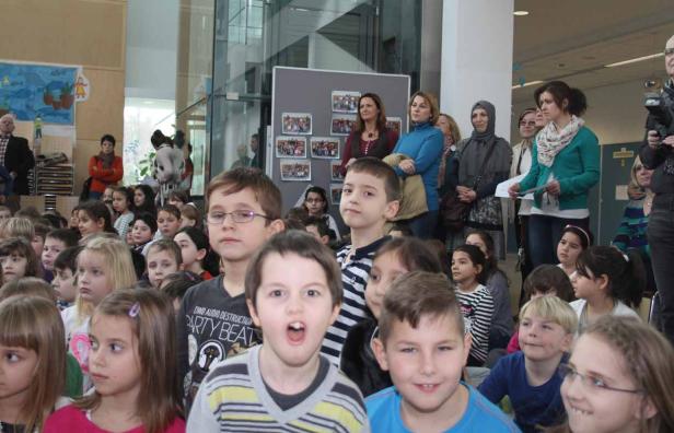 Eine Gruppe von Kindern und Erwachsenen steht in einem Raum.