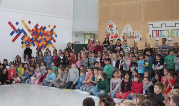 Eine große Gruppe von Kindern sitzt auf dem Boden und schaut in eine Richtung.